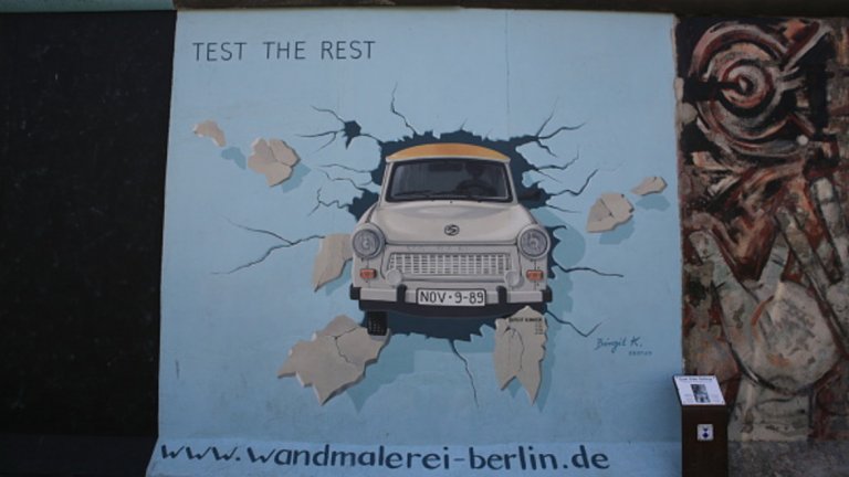 Парче от Берлинската стена с графити на източногермански трабант, който се врязва в тухлите