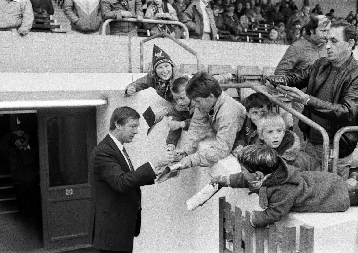 Алекс Фъргюсън (все още без „сър“ пред името си) дава автографи на малки фенове на Оксфорд Юнайтед на „Манор Граунд“ преди първия си мач начело на Манчестър Юнайтед през 1986 г.