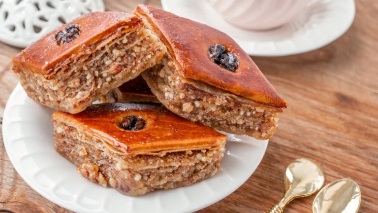 Айле сладкишЗапочваме този богат сладкиш, като си приготвяме захарен сироп от 3 чаши вода и 3 чаши захар с малко лимонов сок и лимонова кора. Оставяме да се охлади. През това време слагаме корите в намаслена тава по следния начин – вадим кора, нагъваме я на хармоника и редим. Поръсваме с малко разтопено масло.
След това приготвяме кексова смес от чаша кисело мляко, чаша брашно, чаша захар, три яйца, пакетче бакпулвер, малко олио и лъжица какао. Заливаме корите за баница, печем на 180 градуса до покафеняване на целия сладкиш и още горещия десерт заливаме със студения сироп. Сервираме добре охладен.