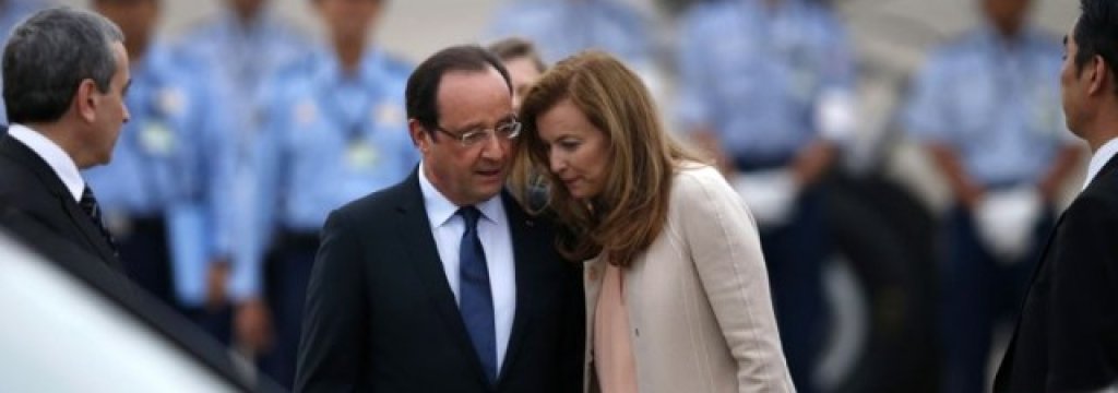 French President Hollande talks with his companion Trierweiler as security officers stand guard upon their arrival at Haneda airport in Tokyo