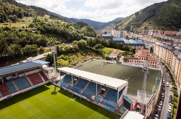 Стадион "Ипуруа" не изглежда най-приятното място да гостуваш. Закачено на хълма край града, мястото е за 5250 зрители, със схлупени трибуни и блокове, надничащи над тях. Тук всичко е малко - Ейбар е 27-хилядно баско градче, но вече втори сезон поред е в елита на испанския футбол.